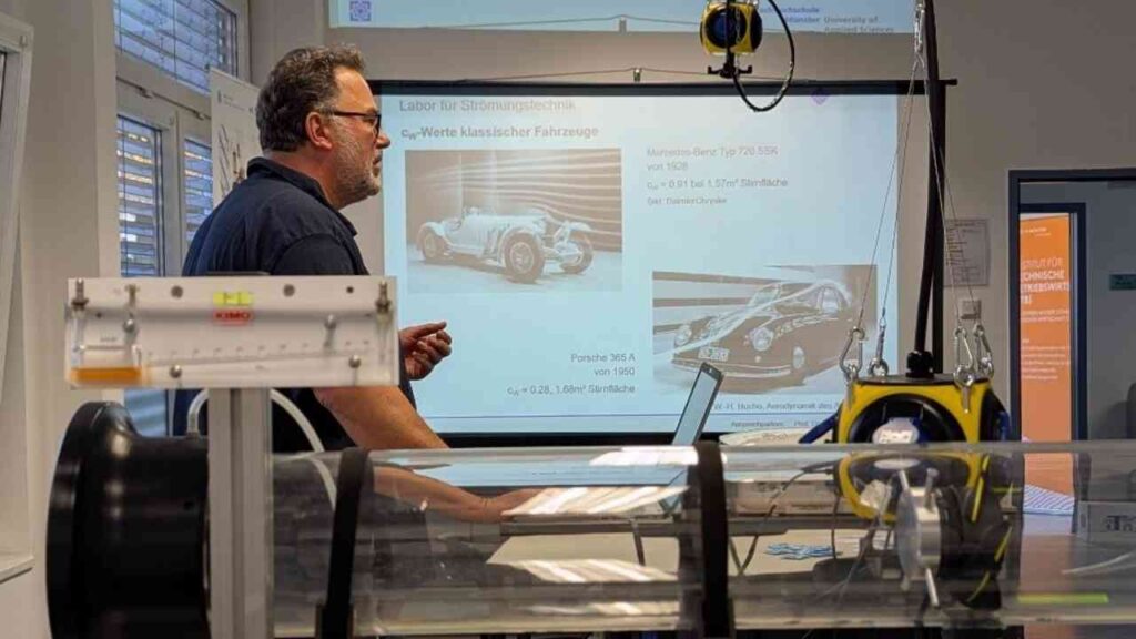Ein Dozent präsentiert Informationen über klassische Fahrzeuge in einem Labor für Strömungsmechanik.