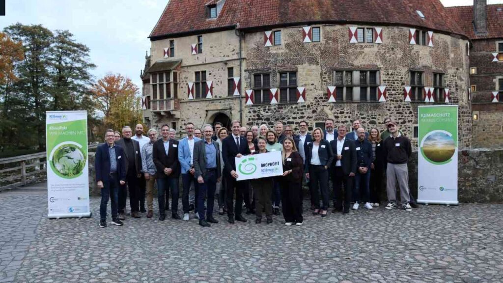 Gruppe von Personen, die an einer Auszeichnung im Freien vor einem historischen Gebäude teilnehmen.