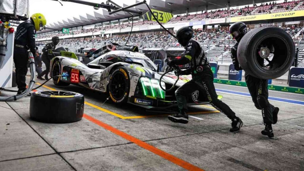 Rennwagen in der Boxengasse während eines pit stops bei einem Autorennen mit Mechanikern, die Reifen wechseln.