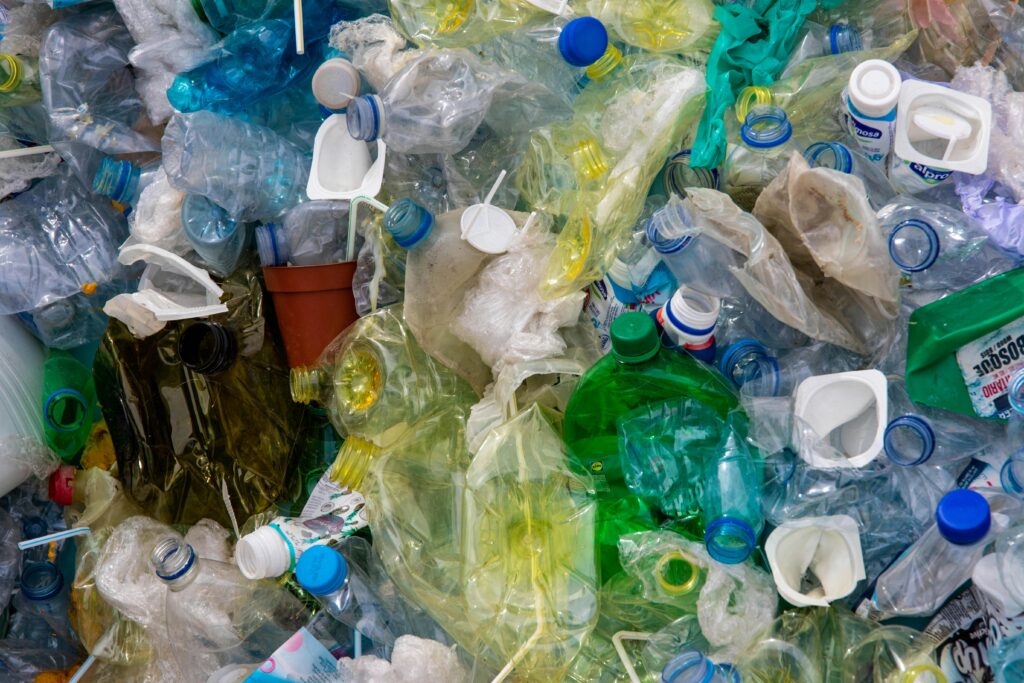 Verschiedene Plastikflaschen und -verpackungen in einem Haufen, darunter transparente und farbige Behälter.