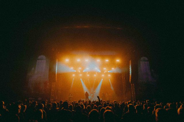 Bühne mit Lichtern und einer Menschenmenge während eines Musikfestivals.