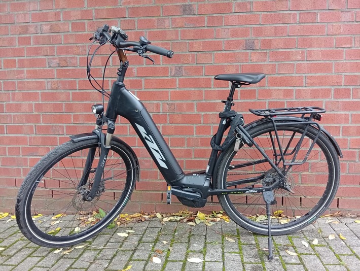 Schwarzes E-Bike mit einem modernen Design und einem stabilen Rahmen, abgestellt vor einer roten Ziegelwand.