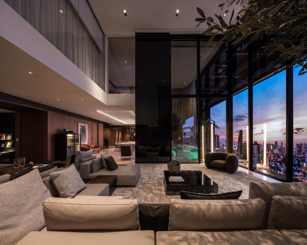 Moderne Wohnlandschaft mit bequemen Sofas und großen Fenstern, die einen Blick auf die Stadt bieten.