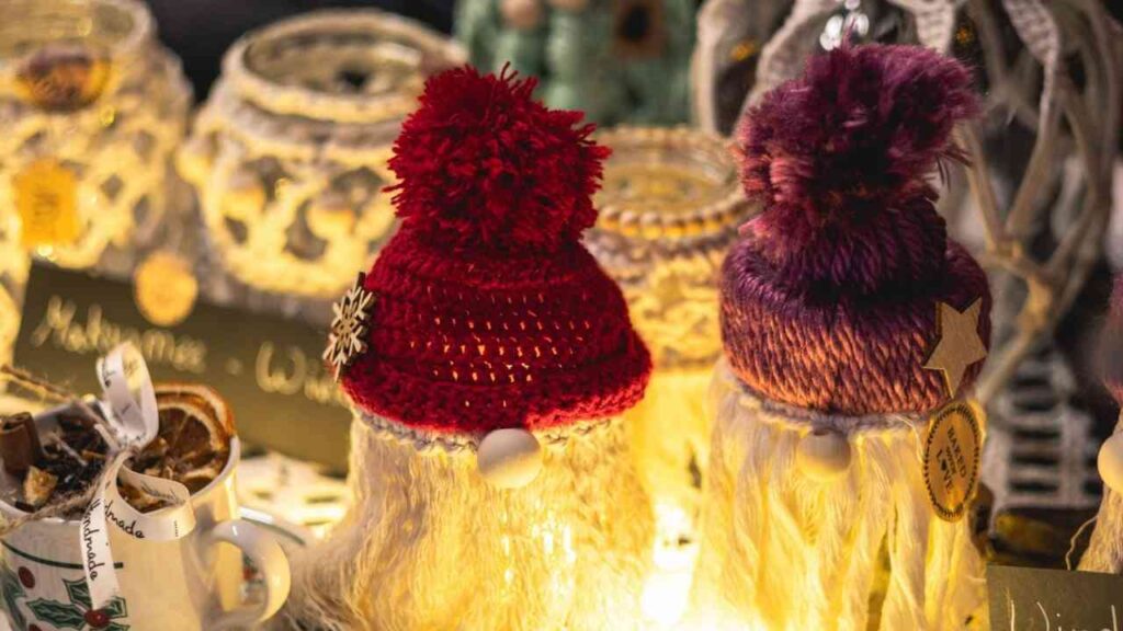 Zwei handgefertigte Weihnachtsfiguren mit roten und lila Mützen, die auf einem Tisch stehen.