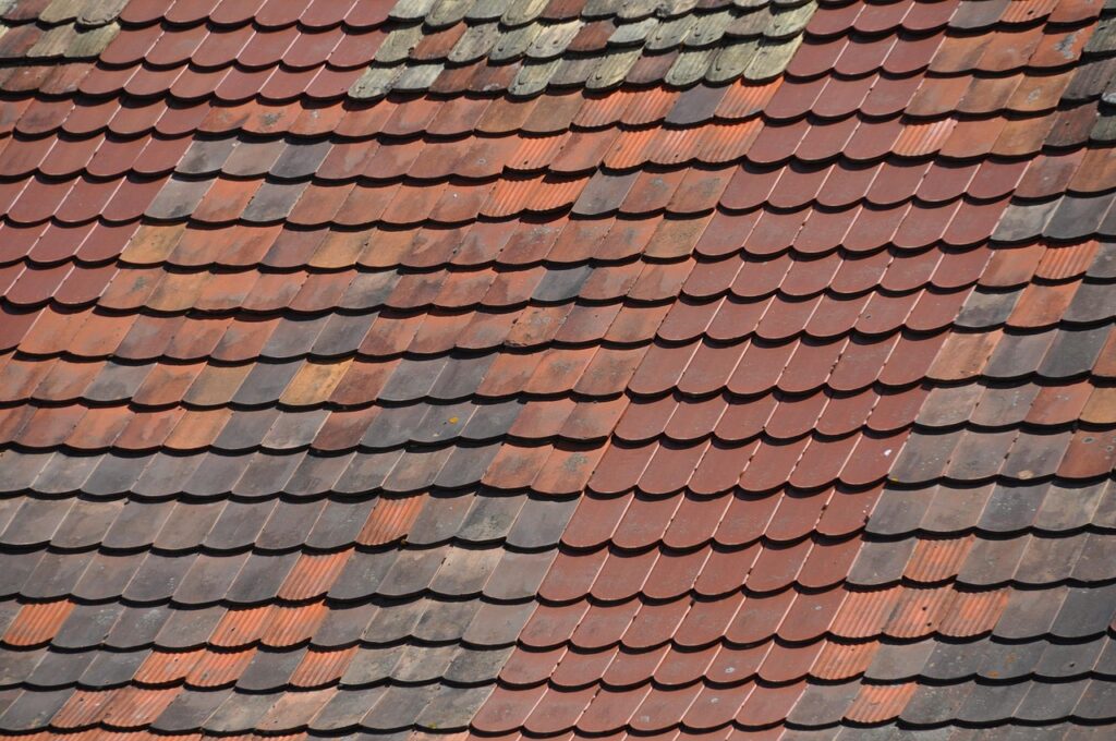 Dachziegel in verschiedenen Farben und Formen auf einem geneigten Dach, das eine traditionelle Bauweise zeigt.