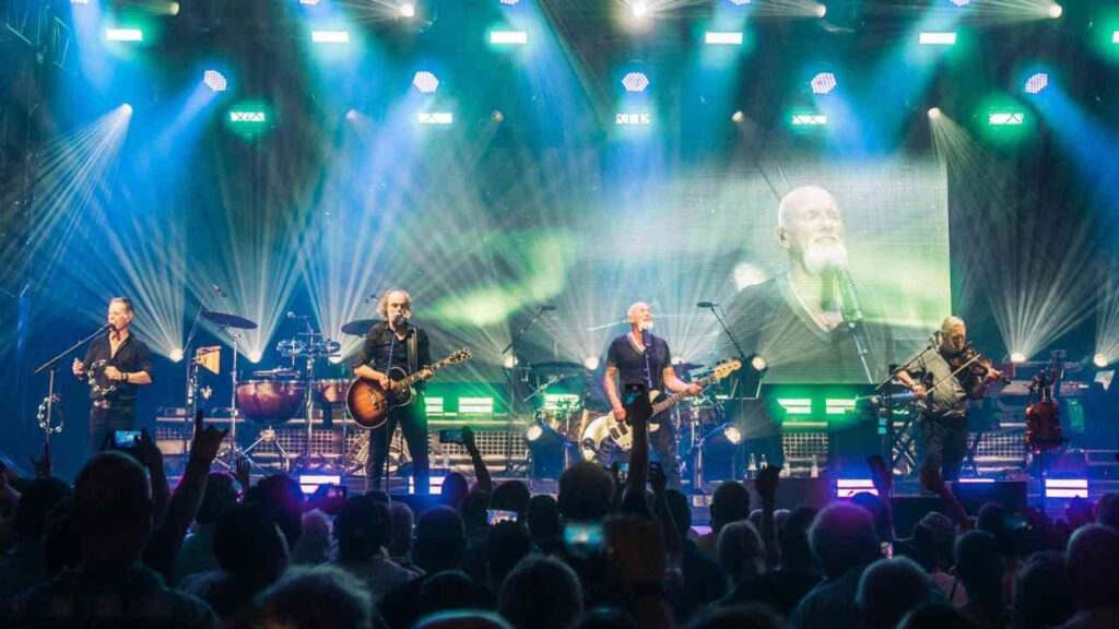 Band Santiano tritt live auf einer Bühne mit Lichtern und einem großen Bildschirm im Hintergrund auf.