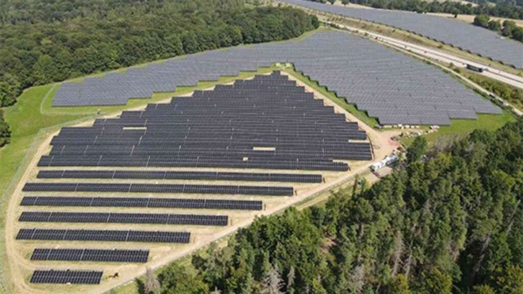 Große Solaranlage mit zahlreichen Solarpanelen in einer strukturierten Anordnung auf einem Grundstück.