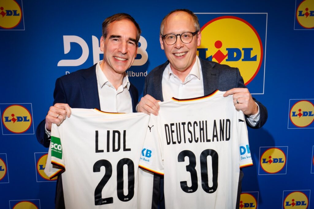 Zwei Männer halten Fußballtrikots mit den Aufschriften 'LIDL 20' und 'DEUTSCHLAND 30' vor einem blauen Hintergrund mit Lidl-Logo.