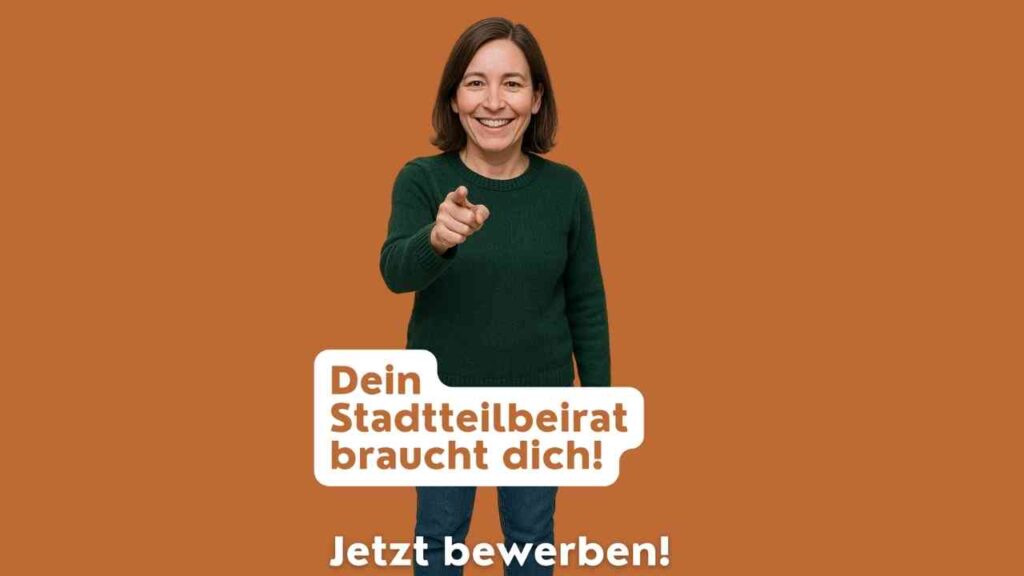 Frau mit braunem Haar in einem grünen Pullover, die auf den Betrachter zeigt, vor einem orangefarbenen Hintergrund.