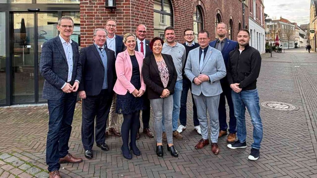 Gruppe von Personen, die an einem Verwaltungstreffen in Rhede-Bocholt-Isselburg teilnehmen, vor einem Backsteingebäude.