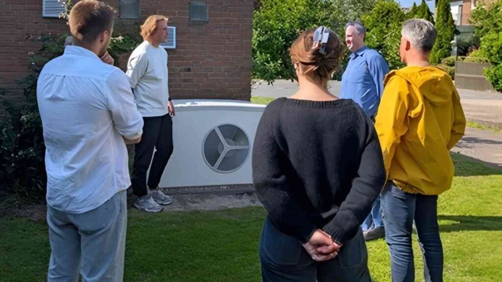 Gruppe von Personen, die sich um eine Wärmepumpe versammeln und diskutieren.
