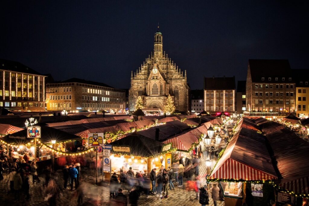 Weihnachtsmarkt in Nürnberg mit festlich beleuchteten Ständen und der Frauenkirche im Hintergrund bei Nacht.