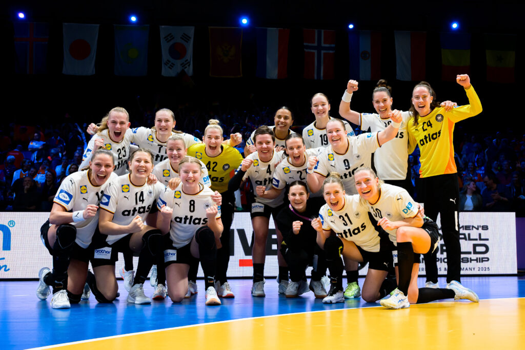 Deutsche Frauenhandballmannschaft posiert nach dem Gewinn des WM-Finales mit Jubel und erhobenen Fäusten.