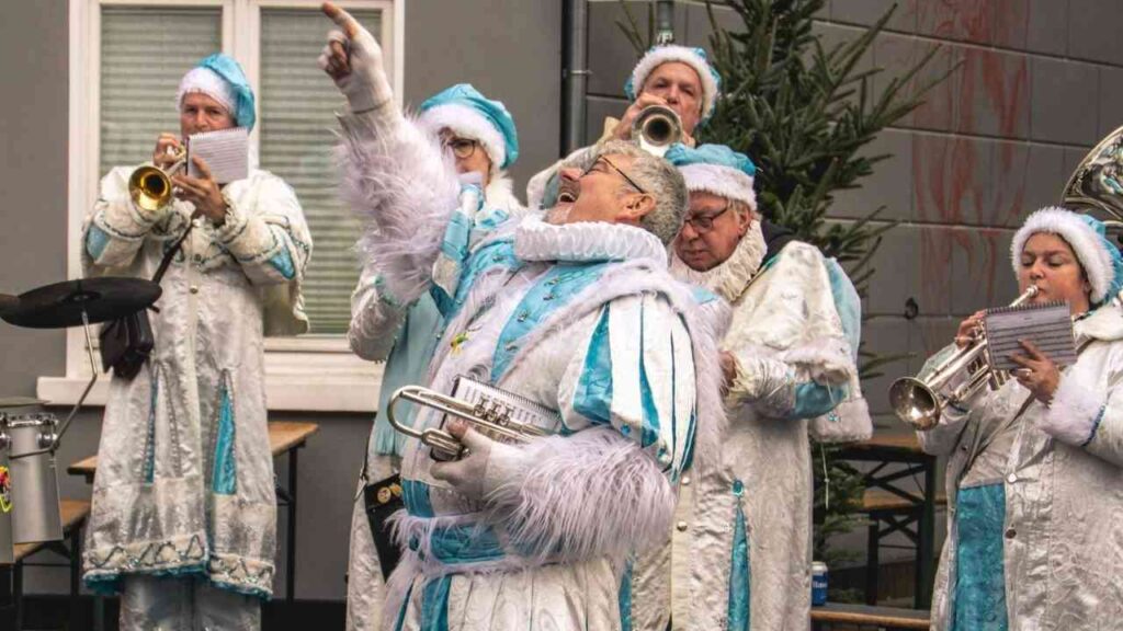 Musiker in festlicher Kleidung mit Trompeten und anderen Instrumenten während einer Aufführung im Freien.