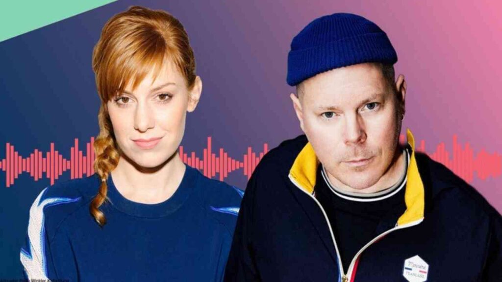 Zwei Podcaster, eine Frau mit geflochtenem Haar und ein Mann in blauer Mütze, vor einem bunten Hintergrund.