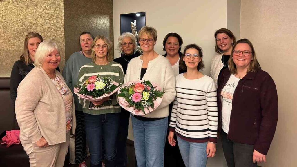 Gruppe von Frauen, die mit Blumensträußen in einem Innenraum posieren.