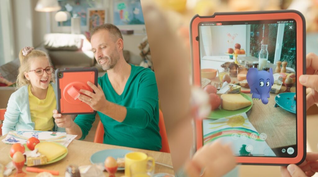 Vater und Tochter interagieren mit einem Tablet, das ein animiertes Elefantenspielzeug in Augmented Reality zeigt.