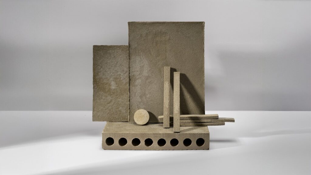 Geometrische Anordnung von Betonobjekten, darunter Platten, Stäbe und Zylinder in neutralen Farbtönen.