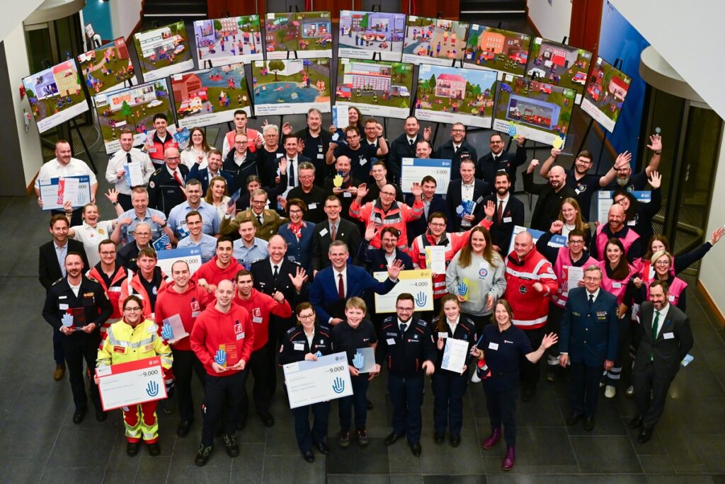 Gruppenfoto von Teilnehmern einer Preisverleihung mit Urkunden und Auszeichnungen in einem Innenraum.