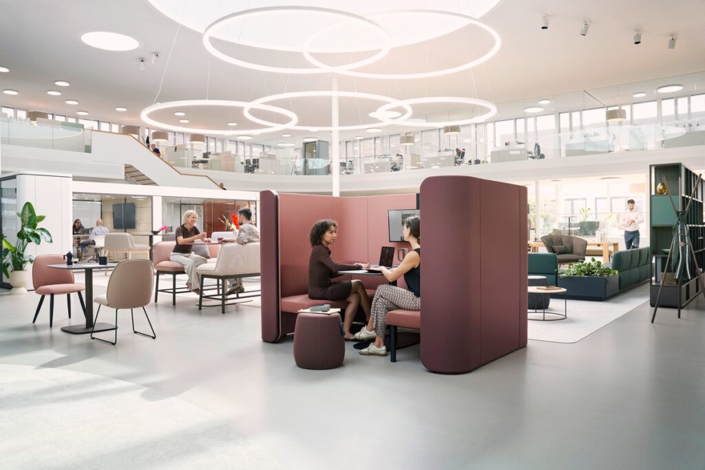 Moderne Büroumgebung mit Sitzgelegenheiten und Besprechungsbereichen für Mitarbeiter in einem offenen Raum.