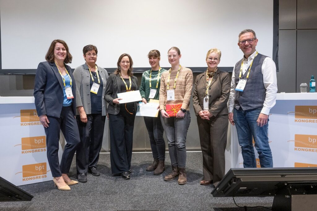 Gruppe von sieben Personen, die bei einer Preisverleihung in Frankfurt auf der Bühne stehen und Urkunden halten.