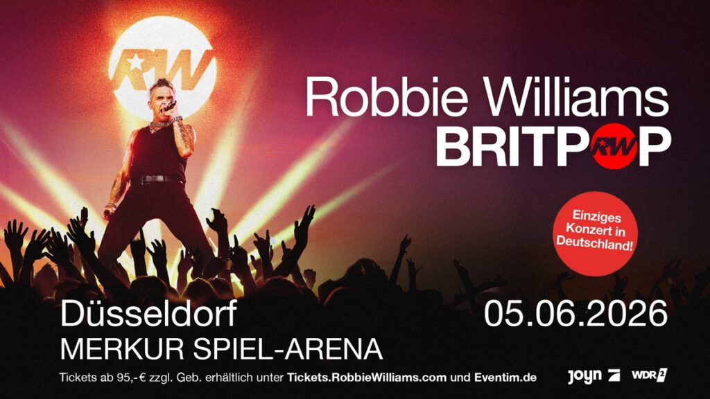 Robbie Williams auf der Bühne während des BRITPOP-Konzerts in Düsseldorf, mit Lichtern und einem großen RW-Logo.