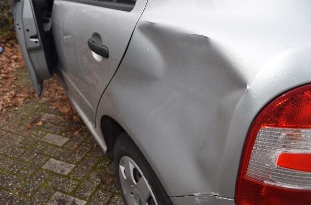 Silbernes Auto mit Delle an der hinteren linken Tür und Kotflügel.