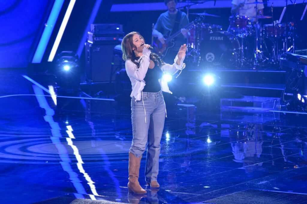 Sängerin auf der Bühne bei 'The Voice of Germany' mit Mikrofon und Band im Hintergrund.