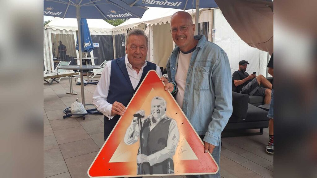 Roland Kaiser signiert das von Mika Springwald gestaltete Verkehrsschild