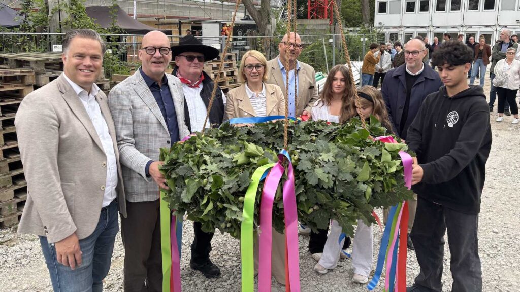 Beteiligte begutachten den Richtkranz beim Richtfest für den Neubau der Friedensschule in Osnabrück