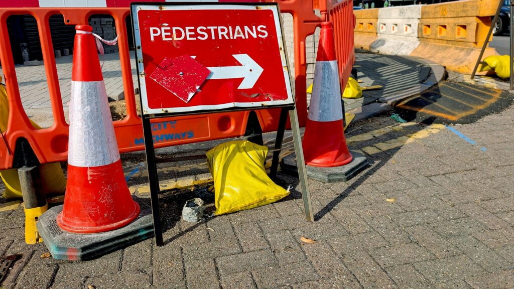 Absperrbaken und Hinweisschild markieren eine Baustelle auf einem Weg