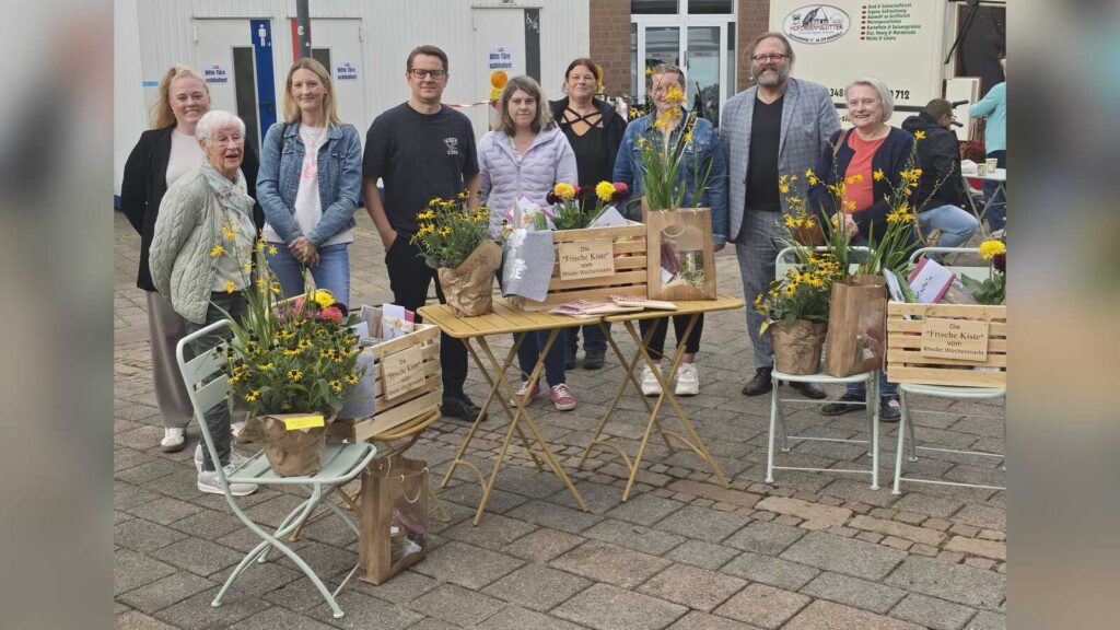 Gewinnerinnen und Gewinner des Gewinnspiels auf dem Rheder Wochenmarkt mit bunten Kisten und Bummeltüten