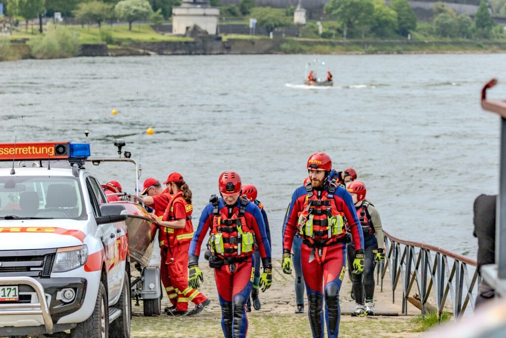 Rettungskräfte in Einsatzkleidung gehen auf ein Boot zu
