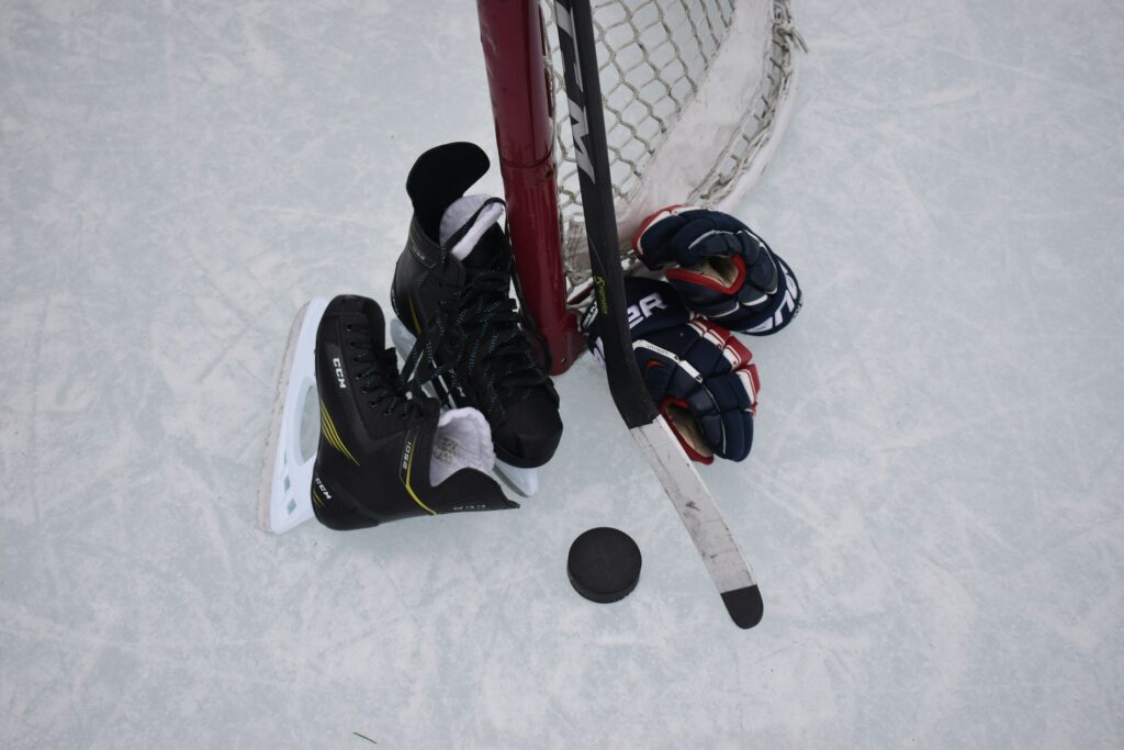 Schlittschuhe, Puck, Handschuhe und Schlaeger auf einer Eisflaeche