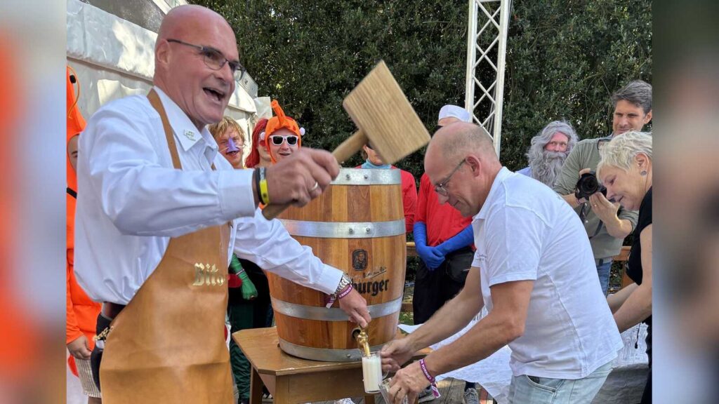 Bürgermeister Jürgen Bernsmann schlägt beim Fassanstich zur Rheder Kirmes das Bierfass an, daneben wird das erste Glas Freibier gezapft