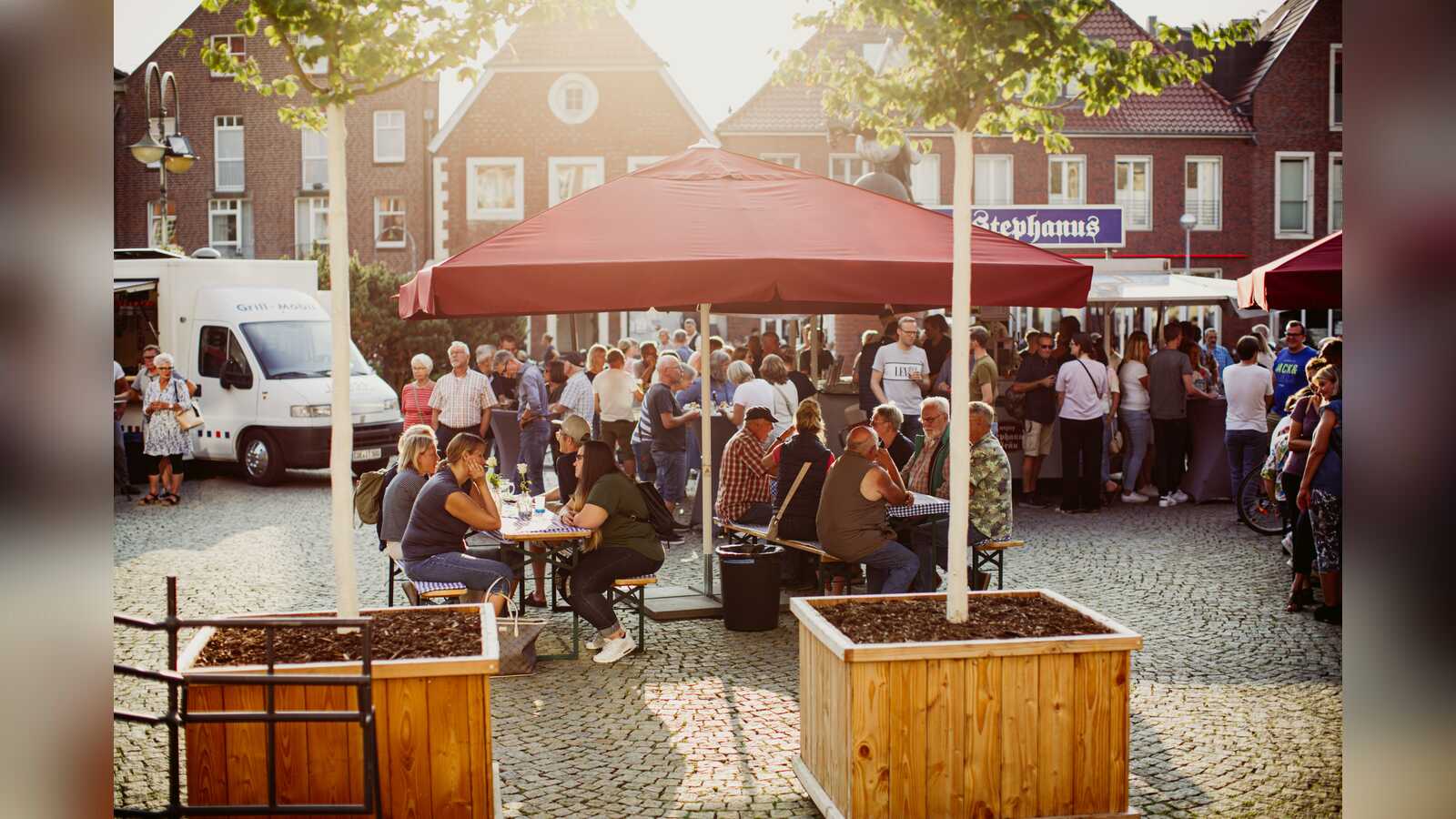 Stehtische auf dem Coesfelder Marktplatz beim Feierabendmarkt im Abendlicht