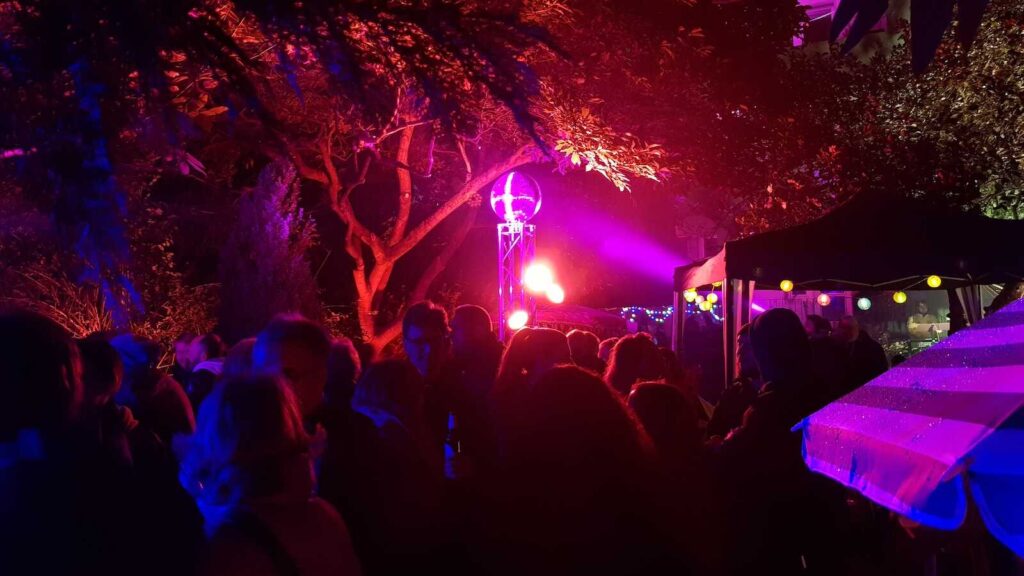 Menschen in einem bunt beleuchteten Hof beim Nachbarschaftsfest Lichter in den Höfen