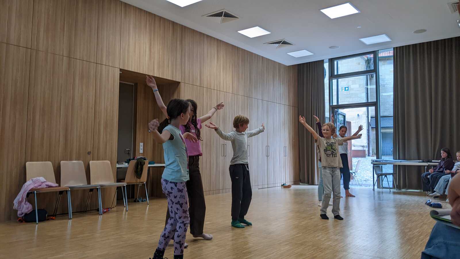 Kinder liegen mit ausgestreckten Armen und Beinen auf dem Hallenboden