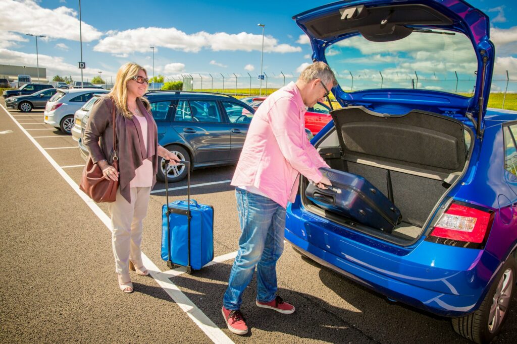 Paar verstaut Koffer im Auto – Symbolbild für Urlaubsreisen