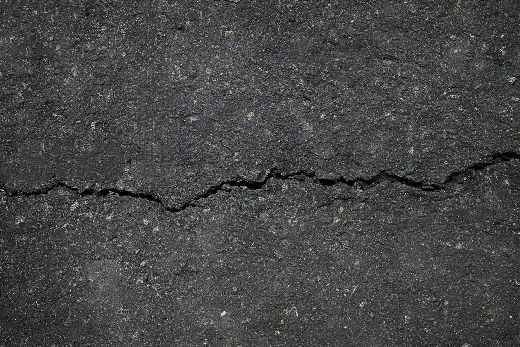 Rissiger Asphalt auf einer Straße, Symbolbild für Fahrbahnschäden