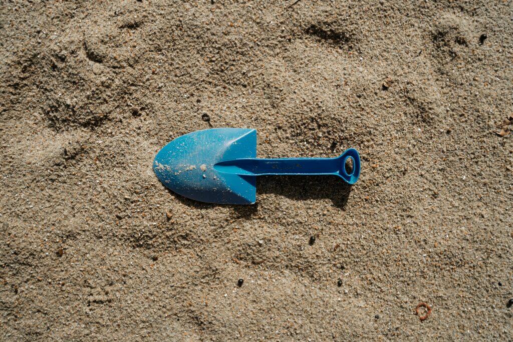 Blaue Spielzeugschaufel steckt im Sand