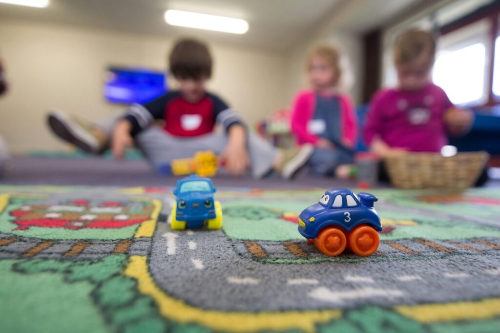 Spielzeugautos auf einem Straßen-Spielteppich in einer Kindertageseinrichtung