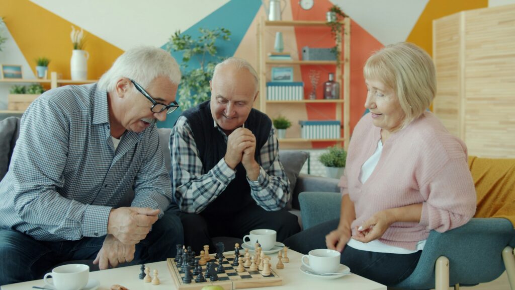 Ältere Menschen sitzen zusammen an einem Tisch und spielen Schach