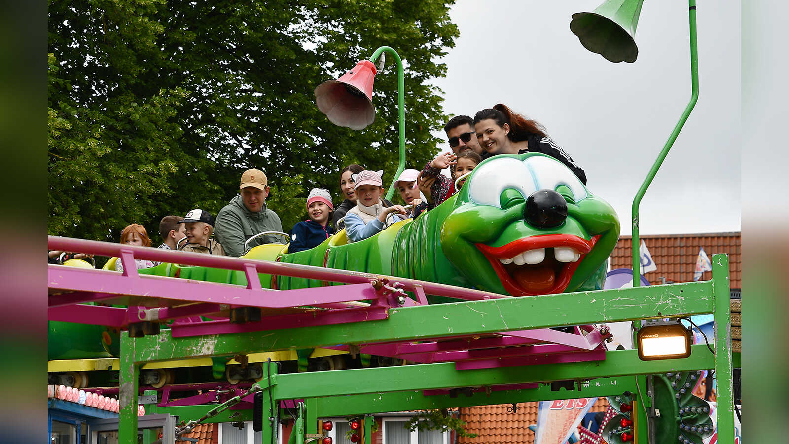 Familien fahren in der neongrünen Raupe des Kids-Coaster