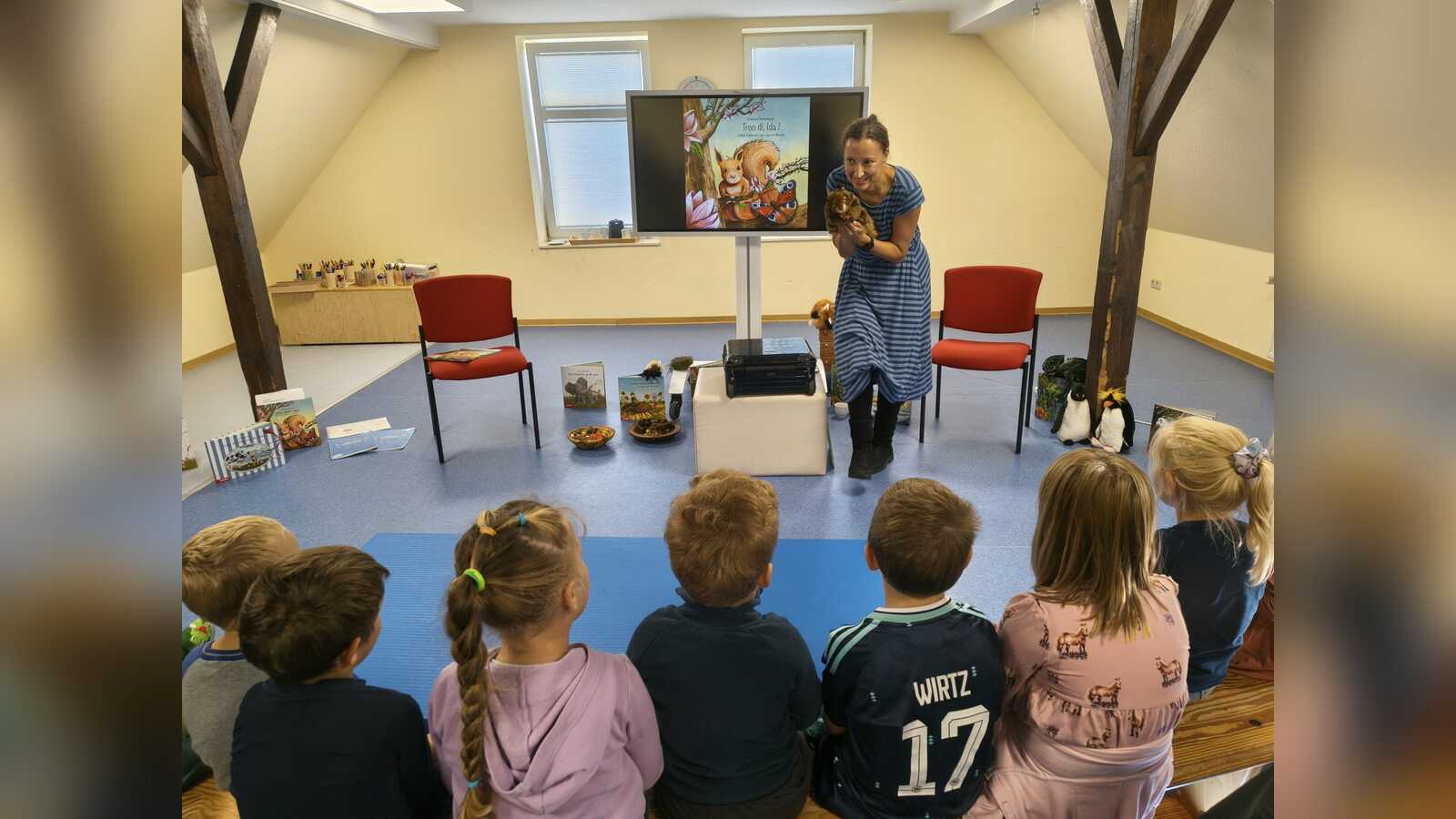 Andrea Reitmeyer liest Kindern des Kindergartens Midlum in der Gemeinde Jemgum aus dem Buch über das Eichhörnchen Ida vor.