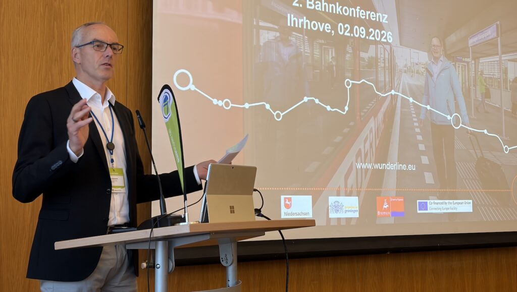 Jan Oostenbrink spricht bei der Bahnkonferenz in Ihrhove am Rednerpult über die Wunderline