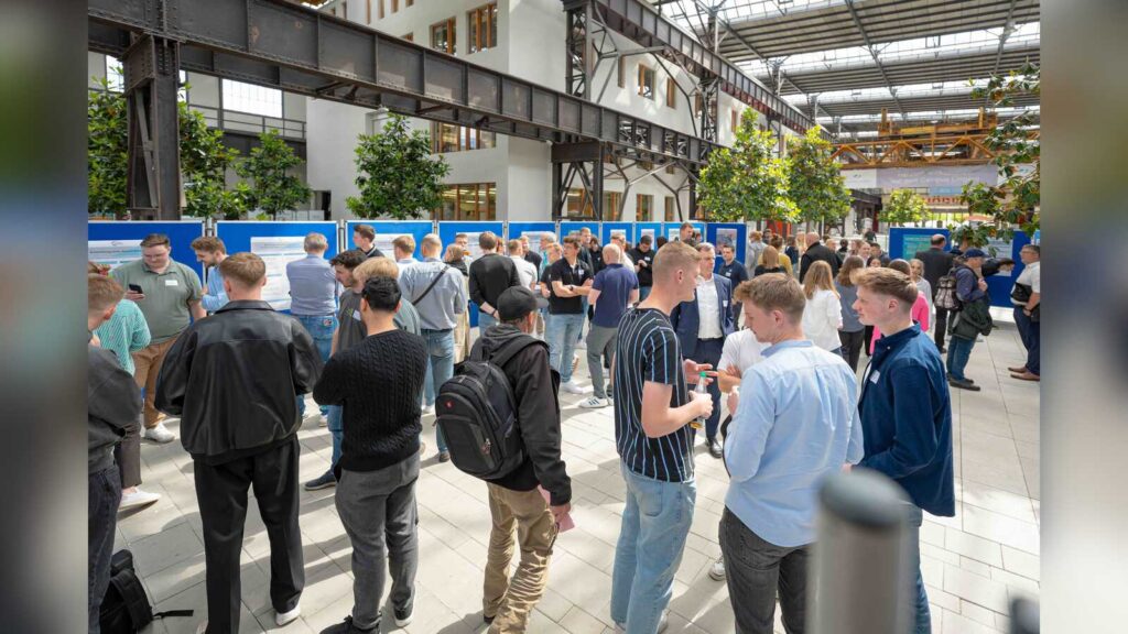 Besucherinnen und Besucher betrachten Projektposter in der Halle am Campus Lingen der Hochschule Osnabrück