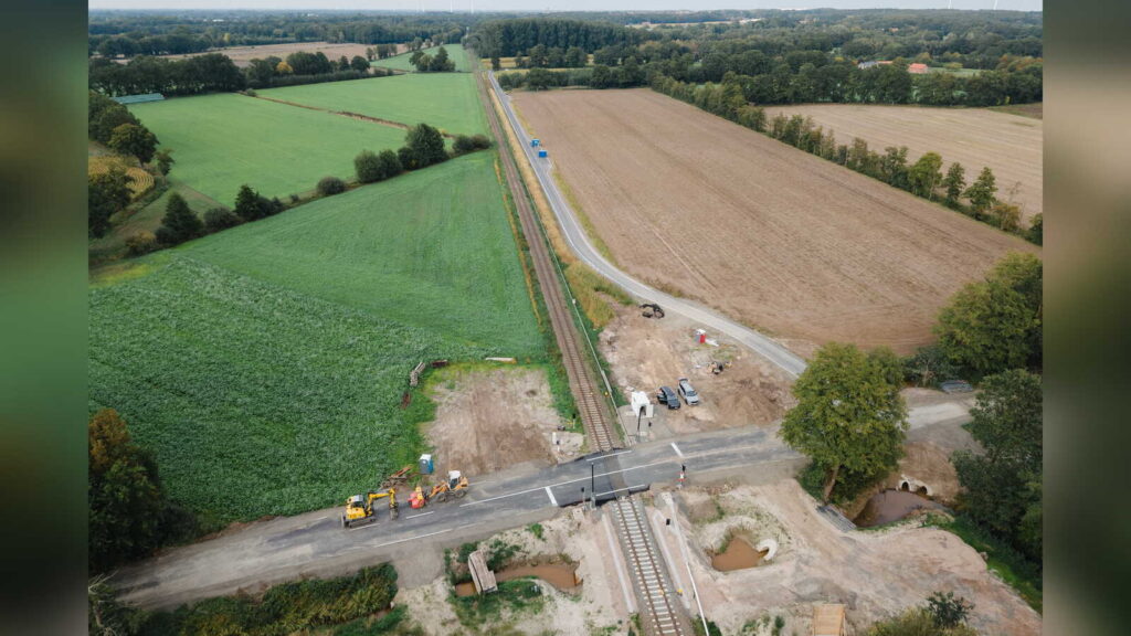 Luftbild der Bahnstrecke in Lohne-Zerhusen mit dem Bahnübergang Brettberger Aue, dem neuen Verbindungsweg entlang der Gleise und dem beschrankten Bahnübergang Pohlwiesendamm