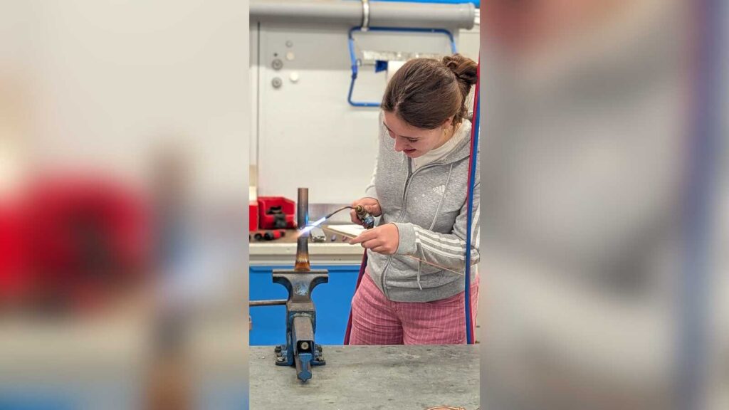 Eine Schülerin probiert das Hartlöten an Kupferrohren aus