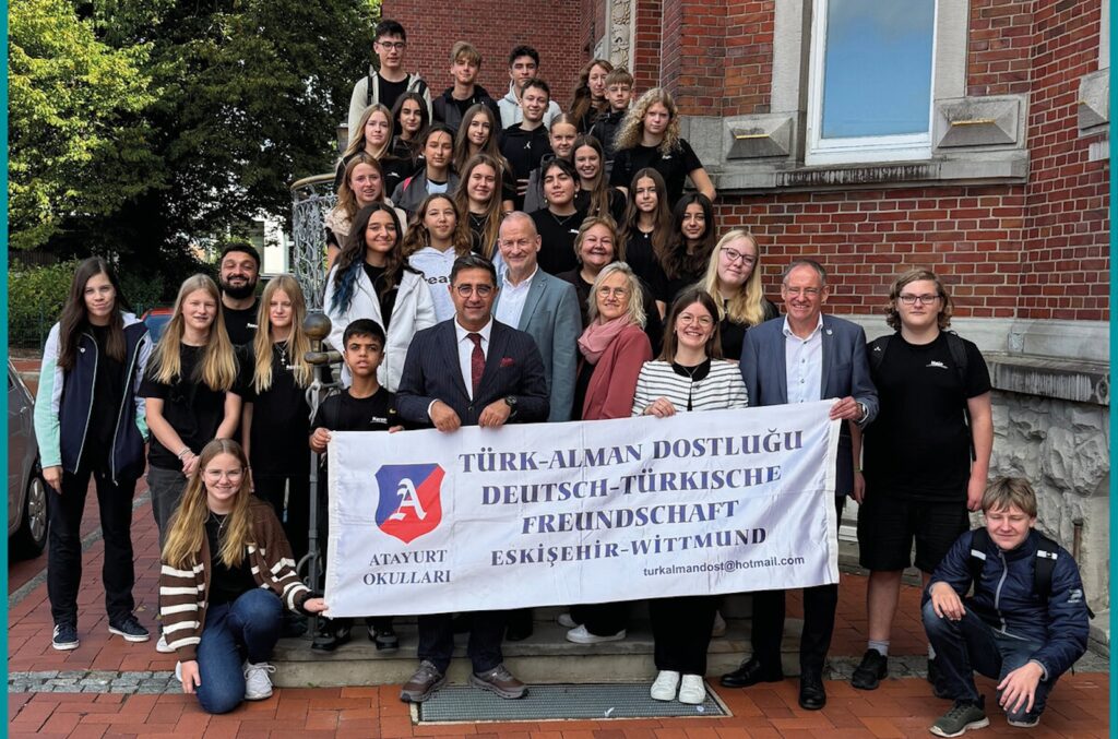 Türkische und deutsche Austauschschülerinnen und -schüler sowie Lehrkräfte und Vertreter des Landkreises Wittmund gruppieren sich für ein Foto vor dem Kreishaus, im Vordergrund ein Banner zur deutsch-türkischen Freundschaft